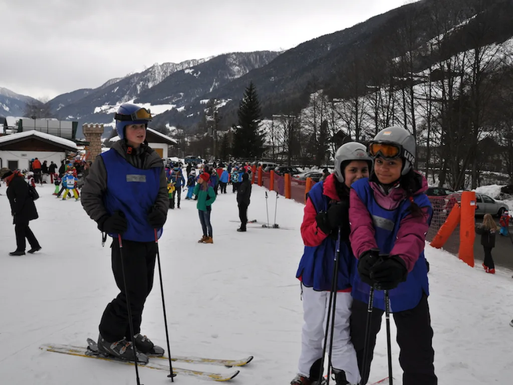 Drei Personen stehen auf Skiern vor dem Absperrnetz.